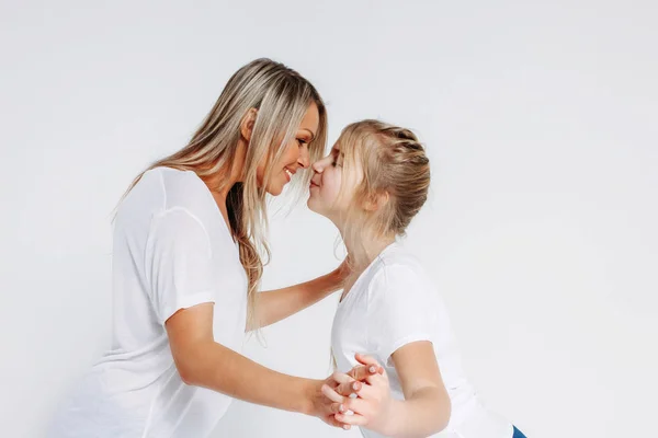 Real mãe e filha em camisetas brancas e jeans abraçando isolado no fundo branco — Fotografia de Stock