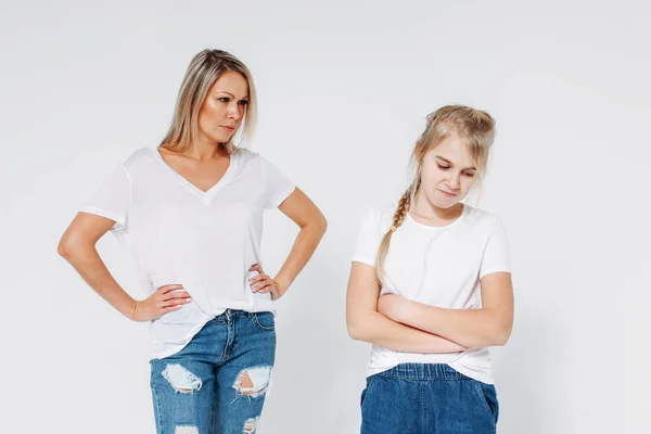 Blonde angry mom and sad daughter in white t-shirts and jeans isolated on white background — 스톡 사진