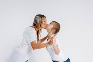 Beyaz tişörtlü ve kot pantolonlu gerçek anne ve kız beyaz arka planda izole edilmiş.