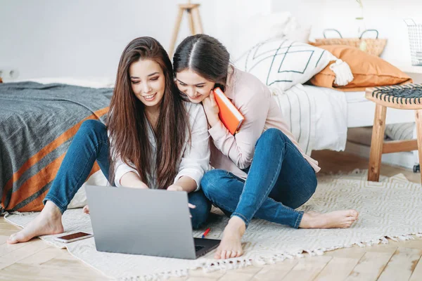 Jong brunette meisjes vrienden studenten in casual doen project samen op zoek naar informatie in internet in laptop op kamer — Stockfoto