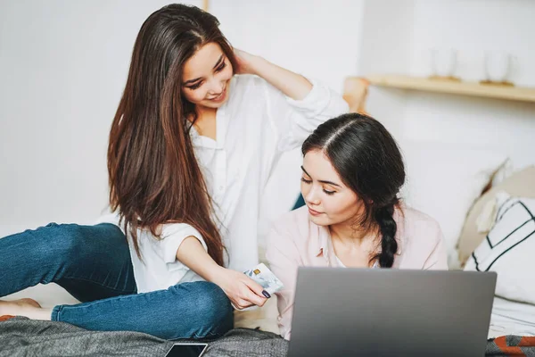 Jonge zorgeloze brunette meisjes vrienden in casual kopen online met creditcard op laptop, winkelen vanuit huis — Stockfoto