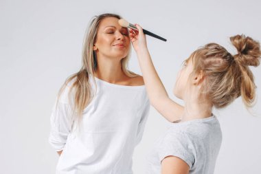 Genç güzel sarışın anne ve kız pijamalarıyla birlikte eğleniyorlar. Beyaz arka planda izole edilmiş, makyajcı kızlar partisi.