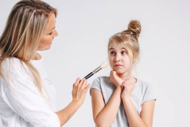 Genç güzel sarışın anne ve kız pijamalarıyla birlikte eğleniyorlar. Beyaz arka planda izole edilmiş, makyajcı kızlar partisi.