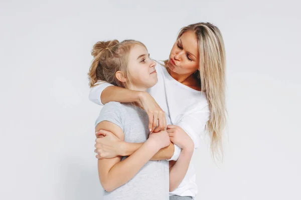 Beautiful blonde mom and daughter preteen in pajamas hugging and having fun isolated on white background — 스톡 사진