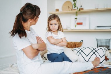 Anne ve kızı oynuyor, kız kızgın, negatif duygular yaşıyor. Aile aydınlık iç mekanda yatar.