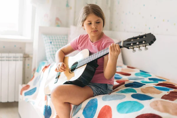 Nettes Zwillingsmädchen Rosa Shirt Spielt Gitarre Sitzen Auf Dem Bett — Stockfoto