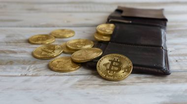 Ahşap bir masa üzerinde deri cüzdan ile altın Bitcoins. Yan görünümü kapatın