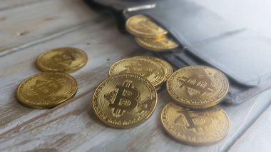 Ahşap bir masa üzerinde deri cüzdan ile altın Bitcoins. Yan görünümü kapatın