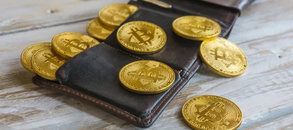 Χρυσή Bitcoins με δερμάτινο πορτοφόλι σε ένα ξύλινο τραπέζι. Κλείνω πάνω θέα πλευρά — Φωτογραφία Αρχείου