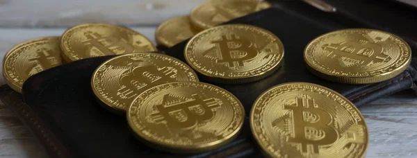 Arany Bitcoins, bőr pénztárca, egy fából készült asztal. Közelről oldalnézetből — Stock Fotó