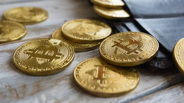 Arany Bitcoins, bőr pénztárca, egy fából készült asztal. Közelről oldalnézetből — Stock Fotó