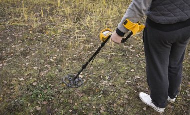 a man with a metal detector is looking for a treasure clipart