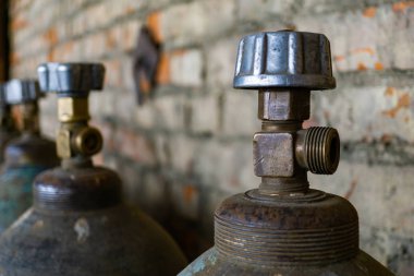 terk edilmiş bir depoda bir tuğla duvar yakınındaki eski yıpranmış tankları oksijen ve diğer gazlar depolamak için stand