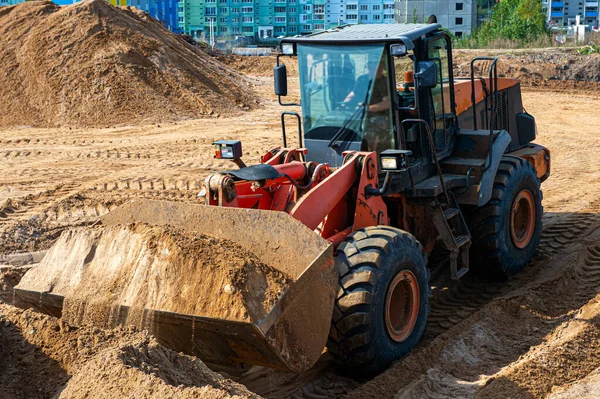 Cargador de ruedas en Eathmoving Works. Máquina de construcción pesada. La cargadora de ruedas transporta arena en un pozo de arena —  Fotos de Stock