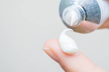 Parmak ucunda bir damla nemlendirici krem. El kremi süren genç bir kız ya da yetişkin bir kadın. Kadın parmağına kolajen nemlendirici serumu döküyor. Hafif arkaplan. yumuşak resim