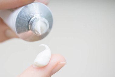 Parmak ucunda bir damla nemlendirici krem. El kremi süren genç bir kız ya da yetişkin bir kadın. Kadın parmağına kolajen nemlendirici serumu döküyor. Hafif arkaplan. yumuşak resim