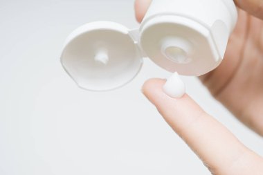 Kadın elleri tüpten parmak derisine nemlendirici krem sürüyor. Güzel kız evinde eline kolajen nemlendirici serumu düşürüyor.