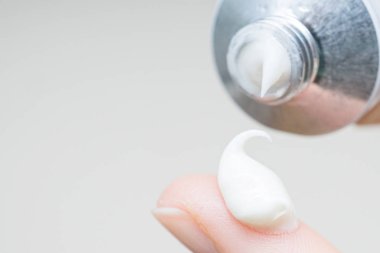 Parmak ucunda bir damla nemlendirici krem. El kremi süren genç bir kız ya da yetişkin bir kadın. Kadın parmağına kolajen nemlendirici serumu döküyor. Hafif arkaplan. yumuşak resim