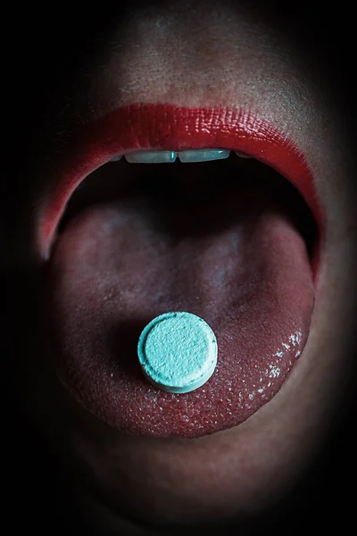tablet in the mouth of the woman, close-up face. Woman taking pill
