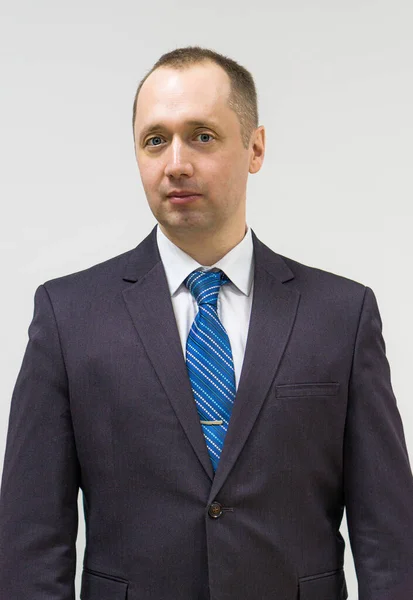 Retrato de um empresário confiante, propositado e bem sucedido vestido em terno cinza e gravata azul no pescoço — Fotografia de Stock