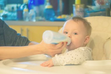 Bebeği besliyorum. Anneler bir yaşındaki bir bebeği biberonla besler. anne bakımı ve bakım. sanat tonu ve gürültü