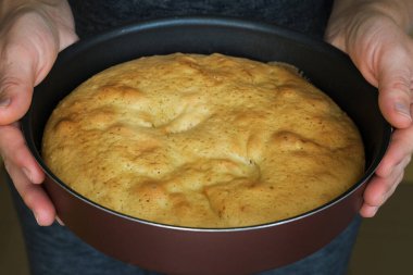 Elinde taze bir turta tutan bir kadın. Lezzetli bir turtayı masaya koyan kadın. Ev hanımı elmalı turtayı masaya getiriyor.