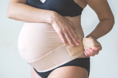 Destekleyici bandaj takan hamile kadına yakın durun. Ortopedik abdominal destek kemeri. Sağlıklı hamilelik kavramı.