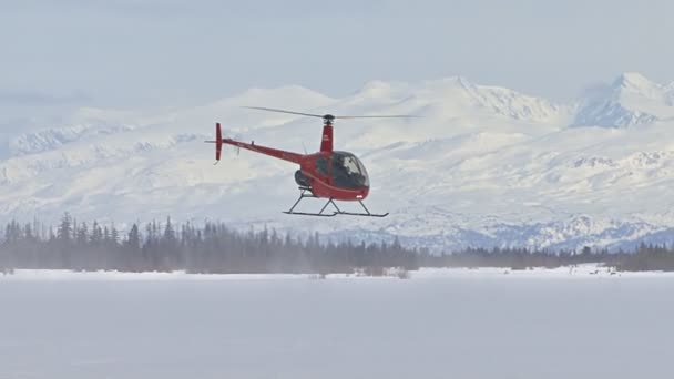 Vörös helikopter lebegett át a behavazott föld — Stock videók