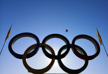 Nicopol, Ukrayna - 9 Kasım 2019: Mavi gökyüzünün arka planında Olimpiyat halkaları. Olimpiyatların halkalarında bayraklar, gökyüzünde uçan kuşlar var..