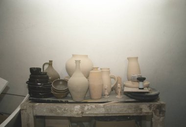 Çamur ürünleri, çömlekçilik atölyesindeki bir rafta seramik yemekler. Durgun ışık ve yaratıcı atmosfer