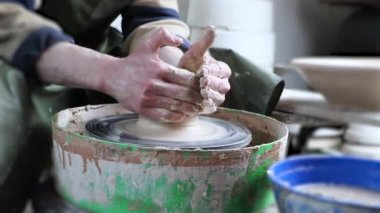 Çömlekçinin elleri çömlekçinin tekerine yakın çekim. Eski geleneksel sanat, el yapımı, kil ve seramik üretim. Yumuşak ışıkta çömlek atölyesi