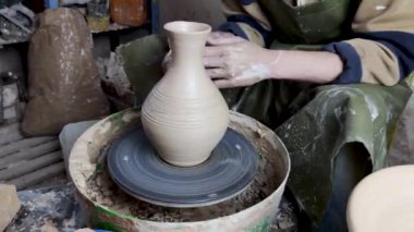 Çömlekçinin elleri çömlekçinin tekerine yakın çekim. Eski geleneksel sanat, el yapımı, kil ve seramik üretim. Yumuşak ışıkta çömlek atölyesi