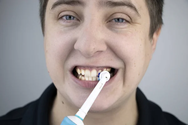 Homem Escova Dentes Com Uma Escova Elétrica Enquanto Olha Para — Fotografia de Stock