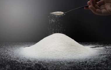 Siyah arka planda şekerli kaşık. Tatlıya bağımlılık kavramı. Granüle şekerin makro fotoğrafı.