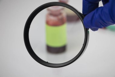 A blood sample for a test for diabetic ketoacidosis (etone  test). The doctors hand holds a magnifying glass in which a test tube with a blood sample for laboratory research. clipart