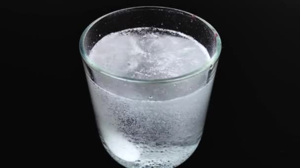 Un comprimé effervescent se dissout dans un verre émettant beaucoup de bulles. Macro vidéo de bulles et de pilules qui se dissolvent .