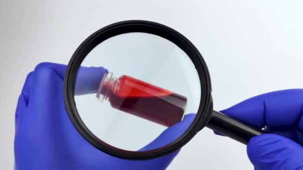 血样检查 医生的手拿着放大镜 其中装有用于实验室研究的血样试管 案文的位置 — 图库视频影像