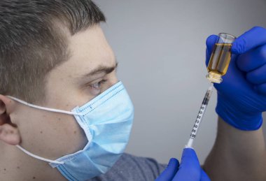 Doktor şırıngaya iğne yapıyor. Bir erkek doktor bir hastaya aşı enjekte etmek üzere. Nüfusun aşılanması ve aşılanması kavramı
