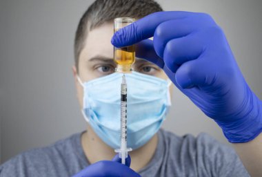 Doktor şırıngaya iğne yapıyor. Bir erkek doktor bir hastaya aşı enjekte etmek üzere. Nüfusun aşılanması ve aşılanması kavramı