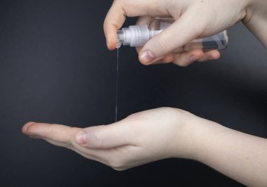 Siyah arka planda antiseptikle kadın elleri işleniyor. Antibakteriyel jel ve dezenfektan. Vücudu mikroplardan koruma kavramı
