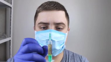 Doktor şırıngayı kontrol ediyor, böylece içinde hava kalmıyor. Büyük damlalar şırıngadan uçar. İğne aşısı için tıbbi ekipman. Hemşire ya da doktor. Sıvı ilaç ya da enjeksiyon. Hastane Sağlık