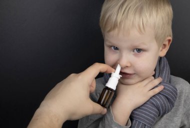Burun akıntısı burun spreyi ile tedavi edilir. Siyah arka planda burun damlaları. Bebek nezlesi ya da virüs enfeksiyonunu tedavi etme kavramı.