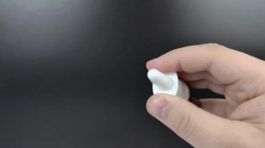 Erkek eller burun için bir ilaç şişesine tıklıyor. Sprey silahından büyük miktarda sıvı damlıyor. Makro video