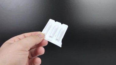 Beyaz ambalajlı fitiller bir adamın elinde. Kullanılmadan önce rektal ya da vajinal fitillerin makro videosu.