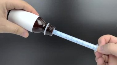 Oral kullanım için plastik bir şırıngada sıvı antipiretik toplanır. Ateşli bir ilacın makro videosu.