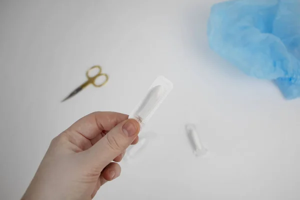 Vaginal or rectal candle in hands on a light background. The drug is in the form of suppositories. The concept of treatment of gynecological diseases and diseases of the rectum