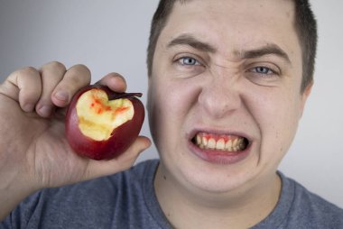 Adamın biri elmayı ısırdı ve dişetlerinden kan geldi. Sakız kanaması, diş eti iltihabı, periodontit ve periodontal hastalık belirtileri..