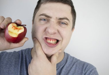 Adamın biri elmayı ısırdı ve dişetlerinden kan geldi. Sakız kanaması, diş eti iltihabı, periodontit ve periodontal hastalık belirtileri..