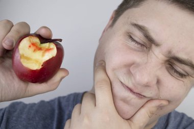 Adamın biri elmayı ısırdı ve dişetlerinden kan geldi. Sakız kanaması, diş eti iltihabı, periodontit ve periodontal hastalık belirtileri..