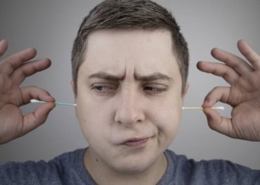Plastik ve bambu keskisi. Bir adam plastikle tahta kulak çubuğu arasında seçim yapar. Pamuk tomurcuklarıyla çevreyi kirlilikten koruma kavramı